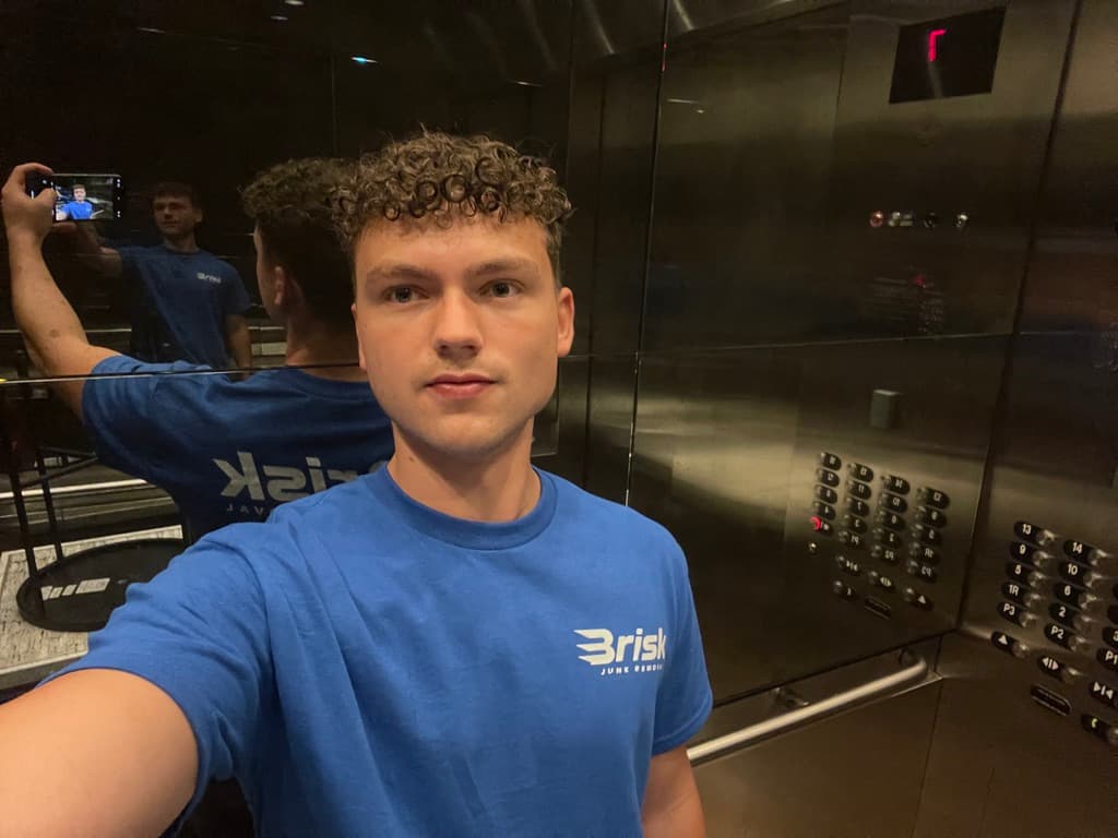 Daniel, founder of Brisk Junk Removal, in a Brisk crew shirt heading up to a job