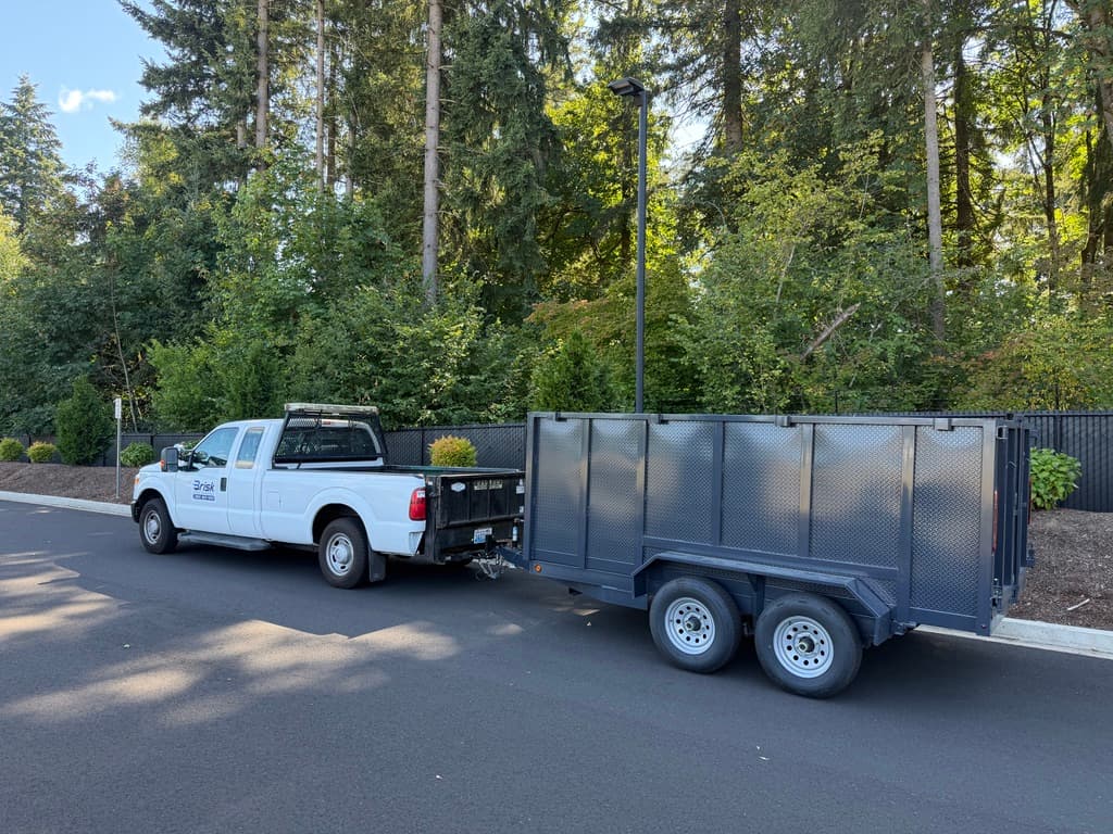 A Brisk Junk Removal truck and dump trailer parked at a customer's home